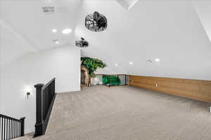 Bonus room featuring ceiling fan, lofted ceiling, and light carpet