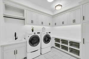 Laundry area with washer and clothes dryer, sink, and cabinets