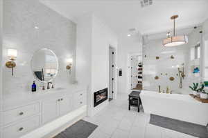 Bathroom featuring separate shower and tub, crown molding, vanity, and tile walls