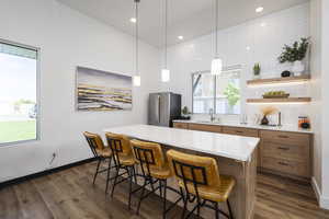 Kitchen with stainless steel fridge, dark hardwood / wood-style flooring, a kitchen island, and a wealth of natural light