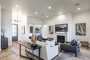 Living room with light hardwood / wood-style flooring, a textured ceiling, and a notable chandelier