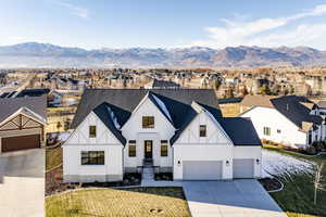 View of front of property with a mountain view, a front lawn, and a garage