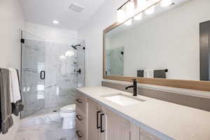 Bathroom with vanity, toilet, and a shower with shower door