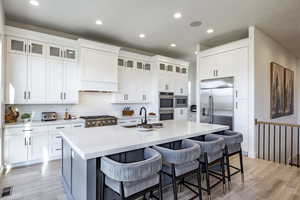 Kitchen with white cabinets, a breakfast bar, and an island with sink