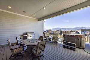 Wooden deck with a mountain view, area for grilling, and a hot tub