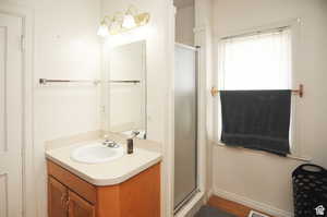 Bathroom with hardwood / wood-style flooring, vanity, and a shower with door