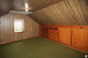 Bonus room with carpet, wooden walls, wooden ceiling, and lofted ceiling