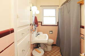 Bathroom with sink, toilet, and tile walls