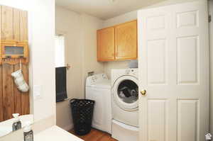 Laundry area with washer and dryer, hardwood / wood-style floors, and cabinets