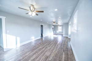 Unfurnished living room with hardwood / wood-style flooring, ceiling fan, and a textured ceiling