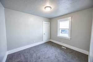 Carpeted spare room with a textured ceiling