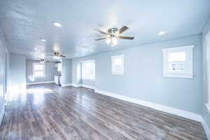 Unfurnished living room with ceiling fan, plenty of natural light, and dark hardwood / wood-style floors