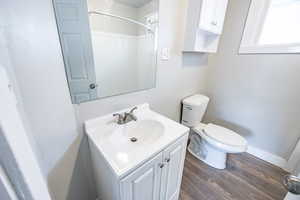 Bathroom with wood-type flooring, vanity, toilet, and walk in shower