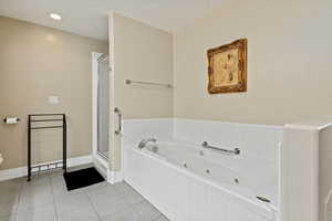 Huge ensuite bathroom within the owner’s suite, featuring Granite Countertops, a jacuzzi tub, and a walk-in shower