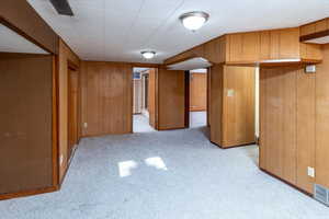 Basement family room with light colored carpet and wooden walls