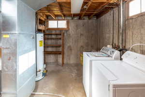 Laundry room featuring heating unit, gas water heater, and washing machine and clothes dryer