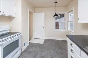 Kitchen featuring white cabinets, decorative light fixtures, and electric stove