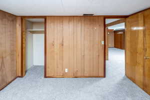 Bedroom featuring light carpet, a closet, and wood walls