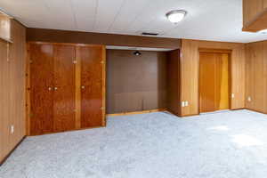 Basement family room featuring light colored carpet and wood walls