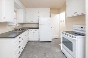 Kitchen with white cabinets, white appliances, and sink