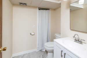 Bathroom featuring vanity, a drop ceiling, and toilet