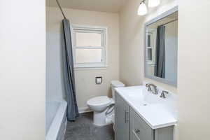 Full bathroom with shower / bathtub combination with curtain, vanity, and toilet