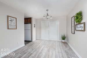 Unfurnished dining area featuring light  wood-style flooring and an inviting chandelier