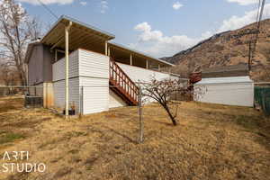 View of side of home with a lawn, central AC, and a mountain view