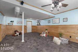 Basement featuring crown molding, ceiling fan, and wooden walls