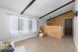 Interior space featuring wood-style flooring, lofted ceiling with beams, and wood walls