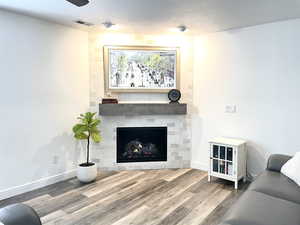 Living room with a fireplace, hardwood / wood-style floors, and a textured ceiling