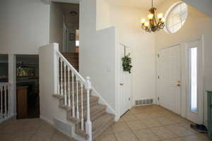 Foyer featuring a notable chandelier, a healthy amount of sunlight, light tile patterned floors, and a high ceiling