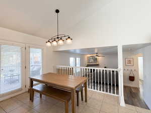 Dining space featuring ceiling fan, light tile patterned floors, and high vaulted ceiling