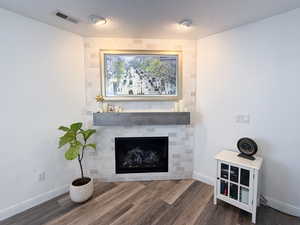 Details with hardwood / wood-style flooring, a textured ceiling, and a tile fireplace