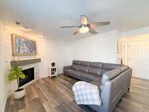 Living room with ceiling fan, hardwood / wood-style floors, and a textured ceiling