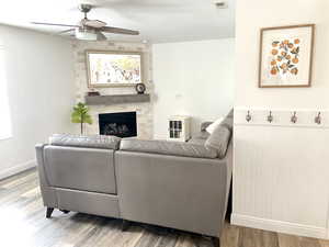 Living room with hardwood / wood-style flooring, ceiling fan, a fireplace, and a textured ceiling