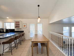 Dining room with light tile patterned flooring, lofted ceiling, and sink