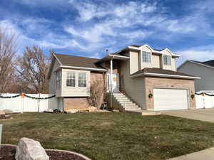 Tri-level home featuring a front lawn and a garage