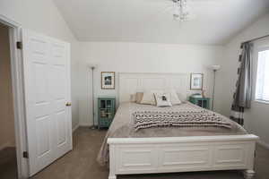 Carpeted bedroom featuring vaulted ceiling and ceiling fan