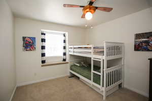 Carpeted bedroom featuring ceiling fan