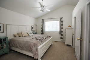 Carpeted bedroom featuring ceiling fan and lofted ceiling