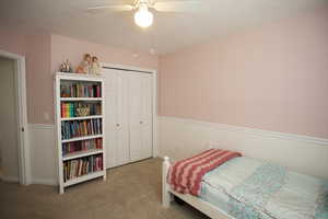 Carpeted bedroom featuring ceiling fan and a closet