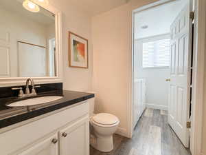 Bathroom with washing machine and dryer, wood-type flooring, a textured ceiling, toilet, and vanity