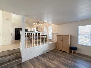 Spare room with dark hardwood / wood-style floors, lofted ceiling, and a textured ceiling