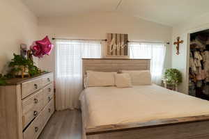 Master bedroom featuring closet, wood-type flooring, and vaulted ceiling