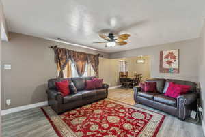 Living room with LVP / wood-style floors, large window, and ceiling fan