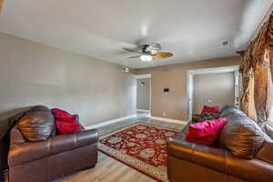 Living room with LVP / wood-style floors, large window, and ceiling fan