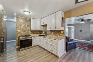 Kitchen with backsplash, light stone-like countertops, white cabinetry, stainless steel range and fridge are negotiable