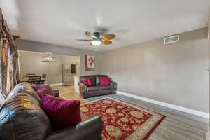 Living room with LVP / wood-style floors, large window, and ceiling fan