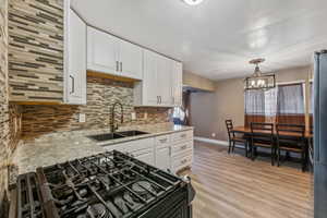 Kitchen featuring white cabinetry, LVP / wood-style floors, decorative light fixtures, and decorative backsplash